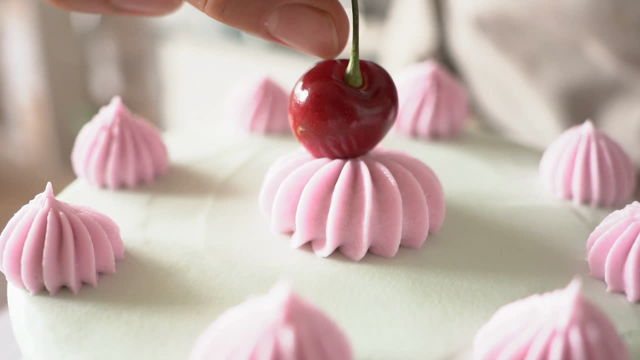 Clip original: una cereza sobre una tarta con rosetones de crema rosa, sin editar