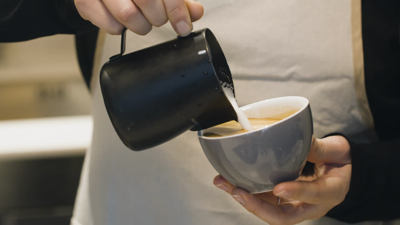 Clip original: una barista vierte leche en una taza, sin editar